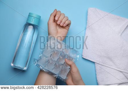 Woman With Ice Pack, Bottle Of Water And Towel On Light Blue Background, Top View. Heat Stroke Treat