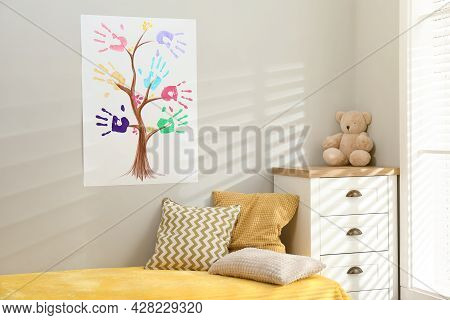 Painting With Family Tree Of Colorful Palm Prints On Light Wall Over Bed In Child's Room