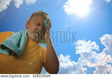 Senior Man With Towel Suffering From Heat Stroke Outdoors, Low Angle View. Space For Text