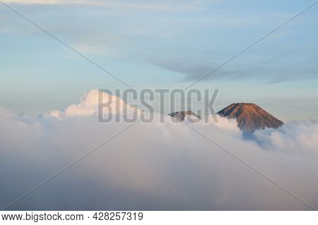 Two Mountain Peaks Visible Behind The Clouds Photo