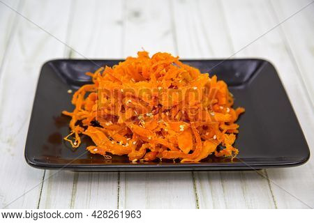 Squid (lat. Teuthida) Shavings In Shanghai On A Black Rectangular Plate With A Wooden Table Backgrou