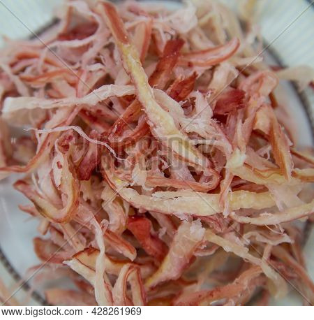Squid Shavings (lat. Teuthida) On A Round Plate With A Wooden Table Background. Food Is A Delicacy S