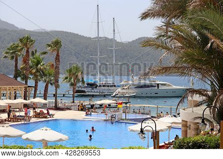 Hisaronu, Turkey - July 2021: View On The Swimming Pool With Palm Trees And Yachts Against The Mount