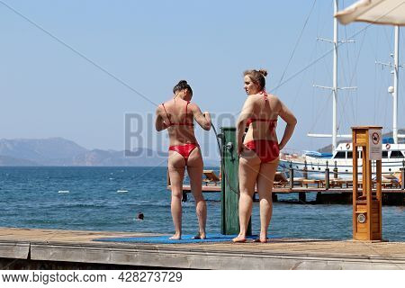 Hisaronu, Turkey - July 2021: Shower On A Beach, Two Young Woman In Red Bikini Washes Standing On Wo