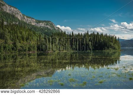 Scenic Lake Reflections During Summer Time. Rocky Peaks And Forest In The Norwegian Nordland County 