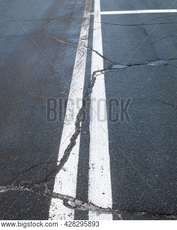 Road With Road Marking Lines. Double Solid White Center Lines. Cracked Asphalt Surface.