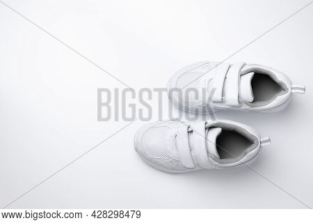 Top View Of Two White Kid Sneakers With Velcro Fasteners For Quick Shoeing With Copy Space Isolated 