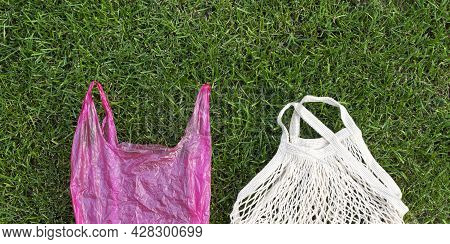 Comparison Of Eco Mesh Cotton Bag And Plastic Shopping Bag On Green Grass Background, Copy Space, Ba