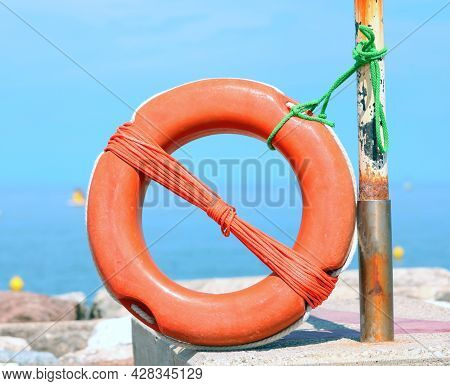 Orange Lifebuoy By The Sea On The Rocks That Can Be Used In Case Of Drowning