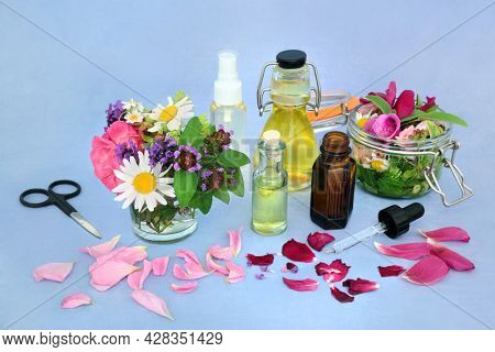 Flower infusion for natural herbal plant medicine with summer flowers and herbs, essential oil bottles and flora steeped in oil. Naturopathic health care concept.