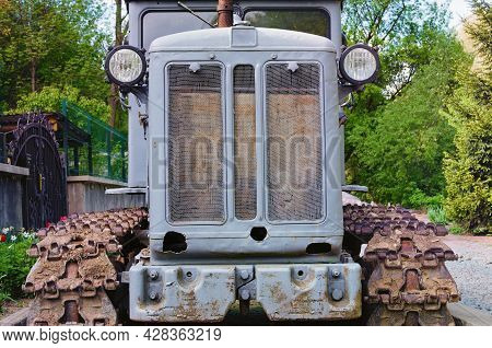 Front View Of Old Crawler Tractor. Detailed View Of Tractor. Soviet Gray Crawler. Nature Landscape B