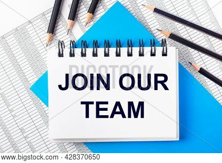 White Notebook With The Text Joi Our Team On The Table Next To Black Pencils On A Blue Background An