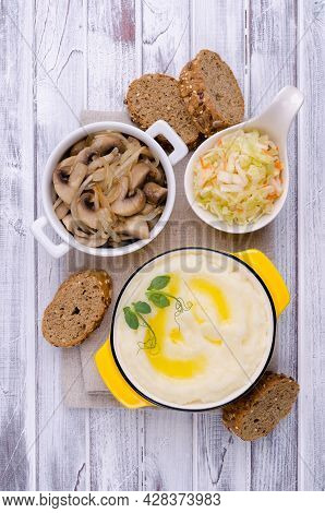 Mashed Potatoes With Butter, Fried Mushrooms With Onions And Salad Of Fresh Vegetables On Light Wood
