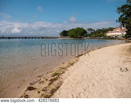 La Toja, Spain - July 24, 2021:
Sandy Beach, Crystal Clear Sea And Bridge At The La Toja Island Luxu