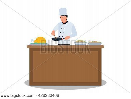 The Chef Prepares The Food. Fried In A Frying Pan At The Kitchen Table, Holding A Wooden Spoon In Hi