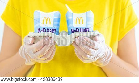 Woman In A Yellow T-short Holding An Ice Cream Mcflurry In Medical Gloves. Delivery Mccafe. Fast Foo