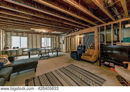 Lounge Inside An Unfinished Basement With Wooden Beams And Wall Insulation
