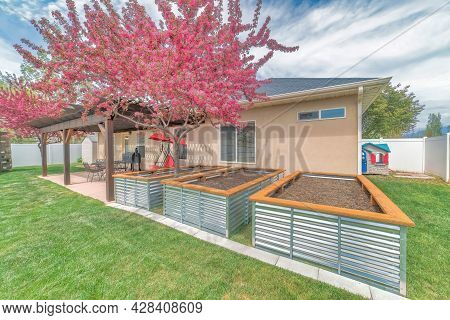 Three Empty Growbeds With Corrugated Steel Wall At The Back Of The House