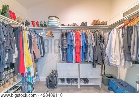 Interior Of A Windowless Walk In Closet With Clothes And Shoes