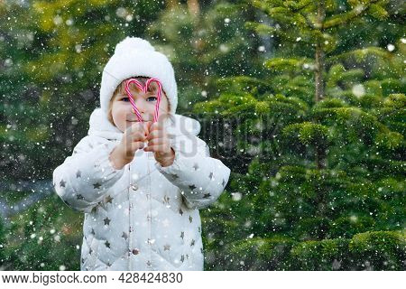 Adorable Little Toddler Girl Holding Christmas Tree And Sweet Candy Cane On Market. Happy Kid Child 