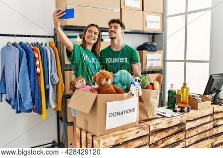 Young hispanic volunteer couple smiling happy make selfie by the smartphone at charity center.