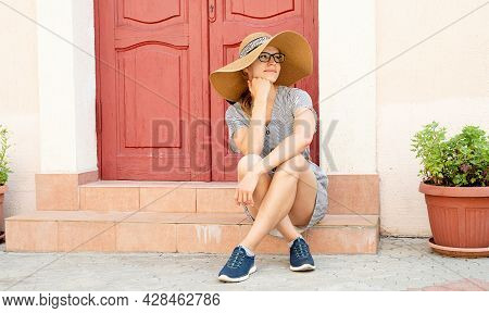 Woman Sitting On Strairs Next To The Bright Red Door