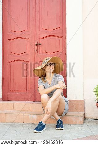 Woman Sitting On Strairs Next To The Bright Red Door