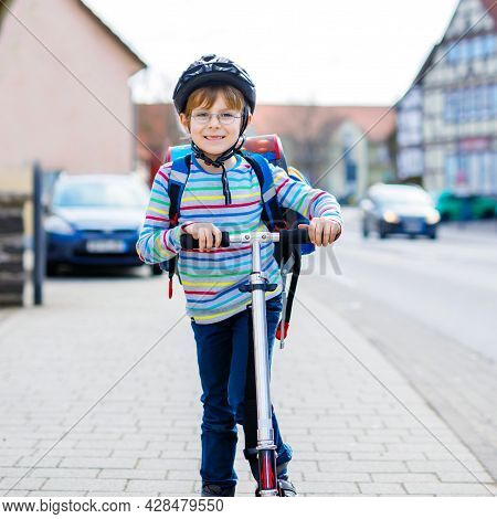 Active School Kid Boy In Safety Helmet Riding With His Scooter In The City With Backpack On Sunny Da