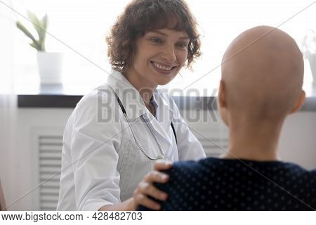 Happy Young Female Oncologist Supporting Bald Woman.