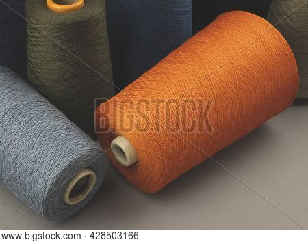 Cones Of Colored Cotton, Woolen Or Synthetic Threads. Bobbins Of Yarn Using In Textile Manufacturing