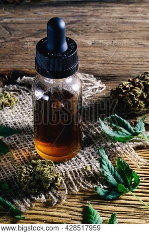 Medical Cannabis Resin Extract Concentrate In Bottle Of Medicine Dropper. Next To Marijuana Buds And