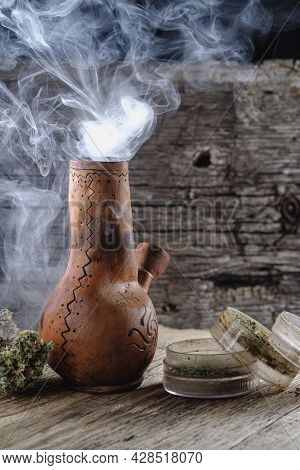 Old Brown Steamung Bong And Open Cannabis Grinder With Chopped Marijuana Weed And Medical Cannabis B
