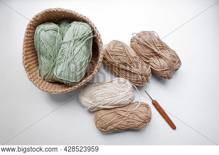 Yarn In A Knitted Basket On A White Background With Hooks. Yarn Of Different Colors. The Concept Of 