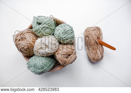 Yarn In A Knitted Basket On A White Background With Hooks. Yarn Of Different Colors. The Concept Of 