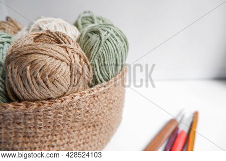 Yarn In A Knitted Basket On A White Background With Hooks. Yarn Of Different Colors. The Concept Of 