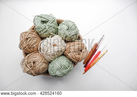 Yarn In A Knitted Basket On A White Background With Hooks. Yarn Of Different Colors. The Concept Of 