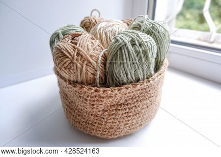 Yarn In A Knitted Basket On A White Background With Hooks. Yarn Of Different Colors. The Concept Of 