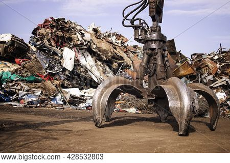 Metal Junk Yard With Hydraulic Lifting Machine With Claw Attachment For Scrap Metal Recycling.