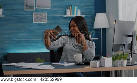 Attractive Black Student Smiling At Camera While Taking Selfie With Smartphone Sitting At Desk Table