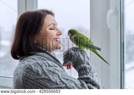 Middle Aged Woman And Parrot Together, Female Bird Owner Talking Looking At Green Quaker Pet