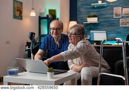 Gray Haired Woman Old Man Analyzing Laptop Screen Computer Monitor At Home On Sofa. Retired Caucasia