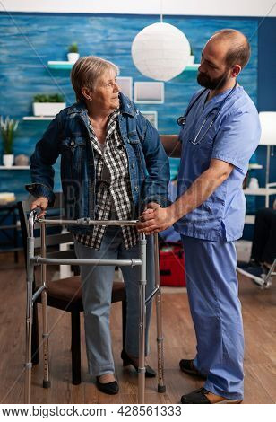 Social Asisstant Man Worker Helping Pensioner Disabled Senior Woman During Recovery Therapy. Healthc