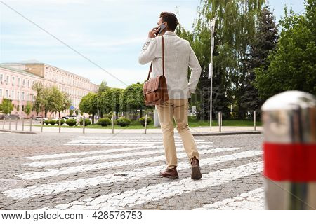 Young Man Talking On Phone While Crossing Street, Back View. Traffic Rules And Regulations