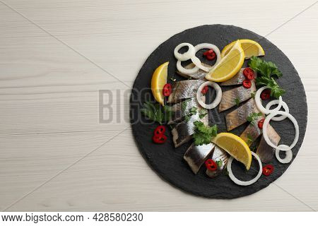 Slate Plate With Sliced Salted Herring Fillet, Parsley,  Chili Pepper, Onion Rings And Lemon On Ligh