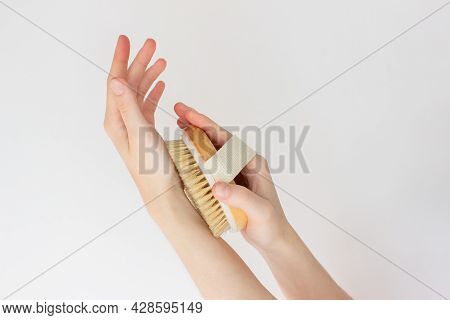 Hand Is Holding Hatural Wooden Body Brush In Front Of White Background. Woman Scrubbing Her Hand. Ma