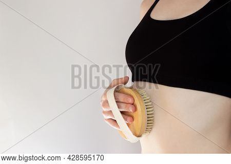 Woman In Black Top Scrubbing Belly. Hand Is Holding Hatural Wooden Body Brush In Front Of White Back