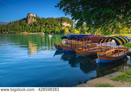 Traditional Touristic Wooden Pletna Boat Moored On The Waterfront. Pletna Rowing Boats On The Alpine
