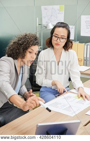Young Female Entrepreneurs Working With Reports, Analyzing Statisctics On Tablet Computer And Pronte
