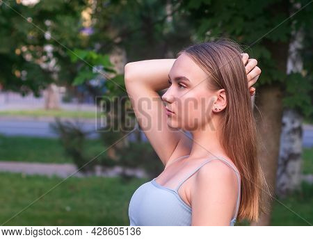 Portrait In Profile Of A Young Beautiful Girl 16 Years Old, With Long Hair, Against A Background Of 