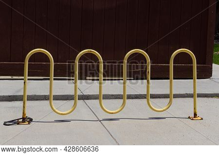 Empty Parking Lot Place For Bicycles With Attached Bicycle Lock At The Brown Wooden Painted Wall Pho